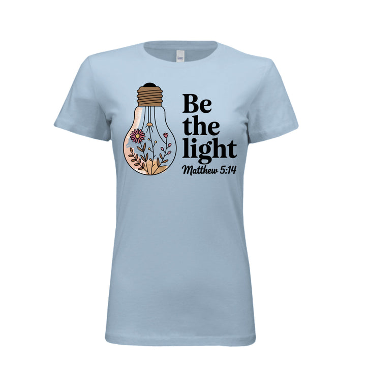 Women's fitted tee in baby blue with a floral light bulb graphic and the words “Be the light – Matthew 5:14” in bold and script fonts.