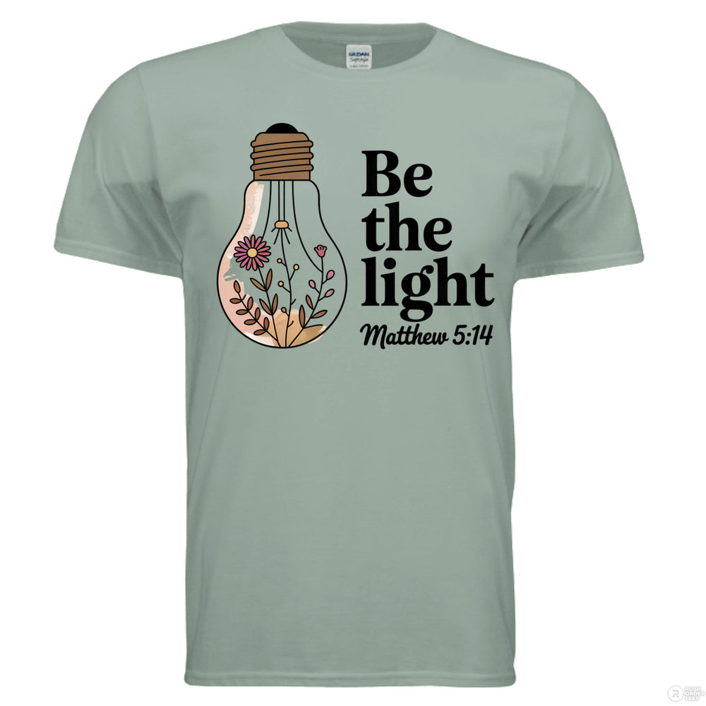 Sage Christian t-shirt with floral light bulb graphic and bold black text reading ‘Be the light – Matthew 5:14’