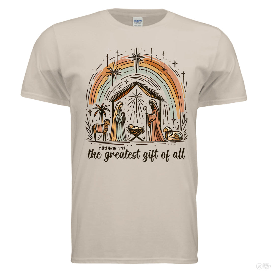 Sand Christian t-shirt with a nativity scene under a rainbow and stars, featuring “the greatest gift of all” and Matthew 1:21 below the design