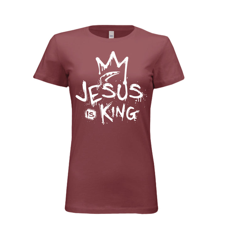 Maroon women’s fitted t-shirt with bold white graffiti-style design reading “Jesus Is King” under a crown. Urban faith statement piece.