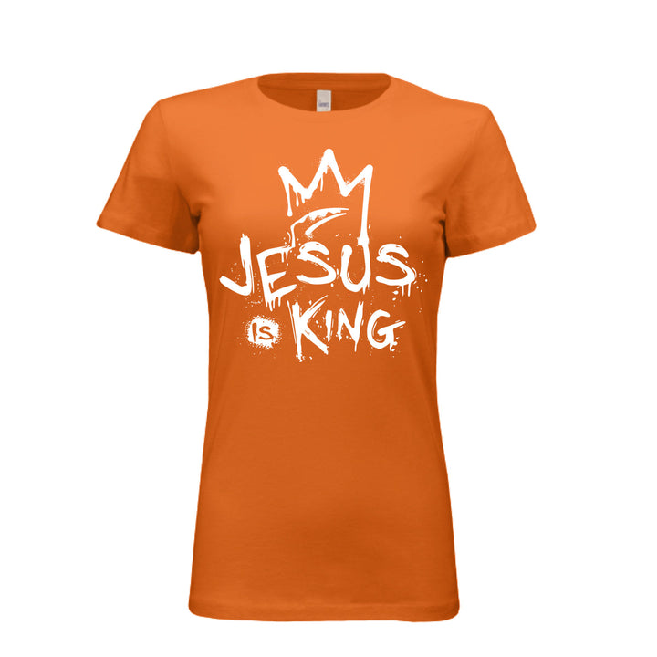 Orange women’s fitted t-shirt with bold white graffiti-style design reading “Jesus Is King” under a crown. Urban faith statement piece.