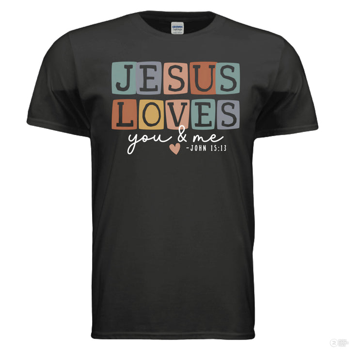Black shirt with pastel block letters reading “Jesus Loves You & Me” and a heart, referencing John 15:13.