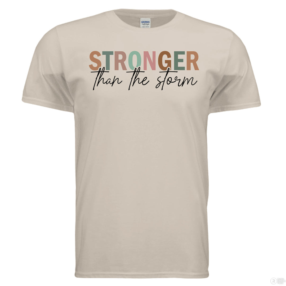 Sand Christian t-shirt with multicolor block and script text reading ‘Stronger than the storm’ in earth tones and black lettering